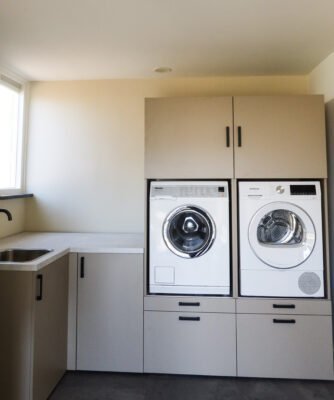 Wasmachine kast op hoogte met veel opbergruimte, een werkblad en een wasbak.